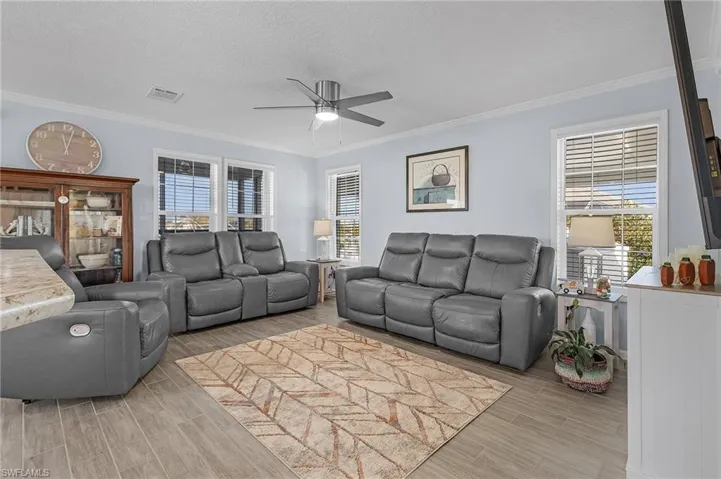 Living room with plenty of natural light, a textured ceiling, and crown molding