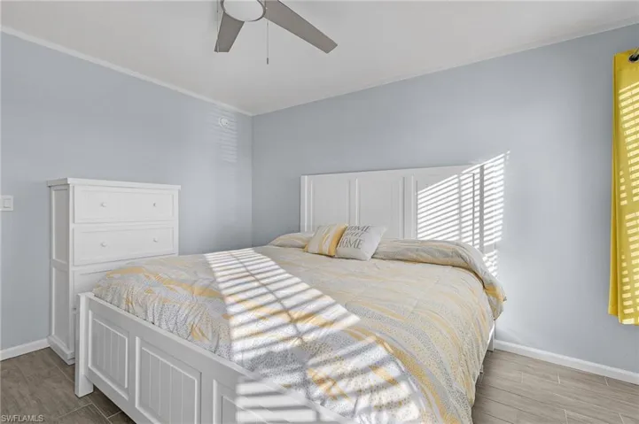 Bedroom featuring ornamental molding, light wood-type flooring, and ceiling fan