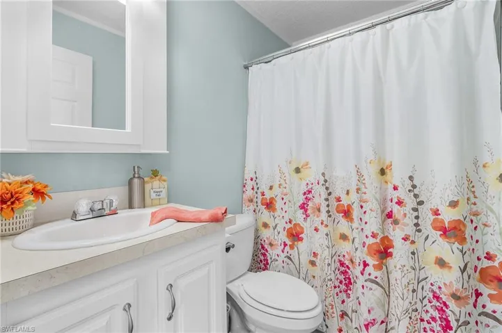 Bathroom with toilet, vanity, a textured ceiling, and walk in shower
