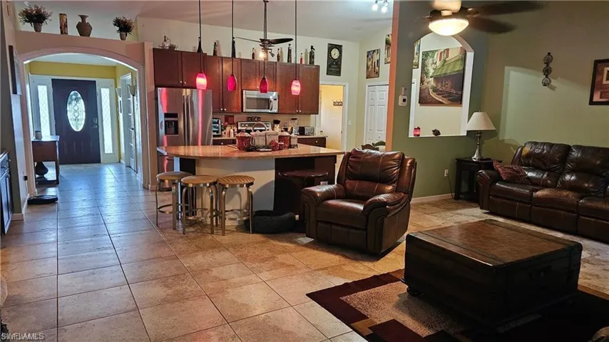 Living room with a ceiling fan, arched walkways, and light tile patterned floors