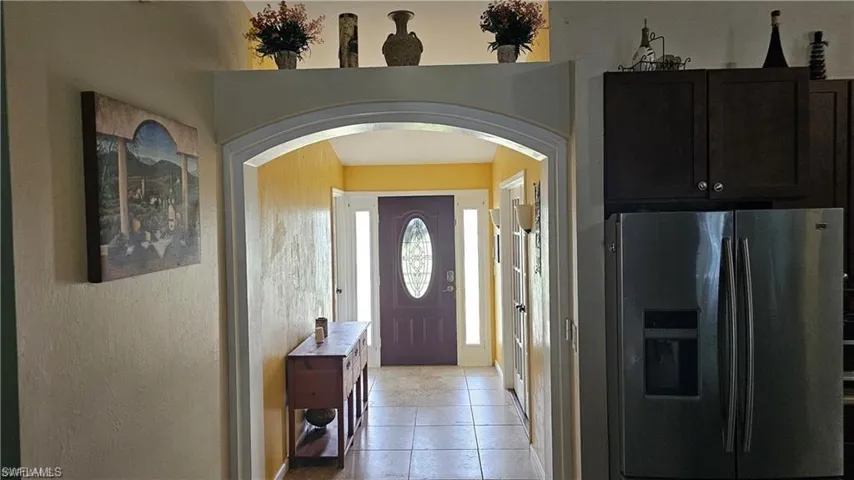 Entrance foyer with arched walkways and light tile patterned flooring