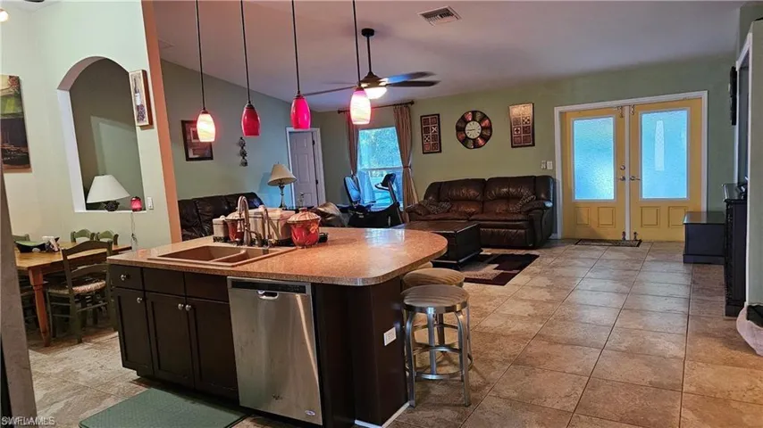 Kitchen featuring open floor plan, dishwasher, ceiling fan, vaulted ceiling, and arched walkways