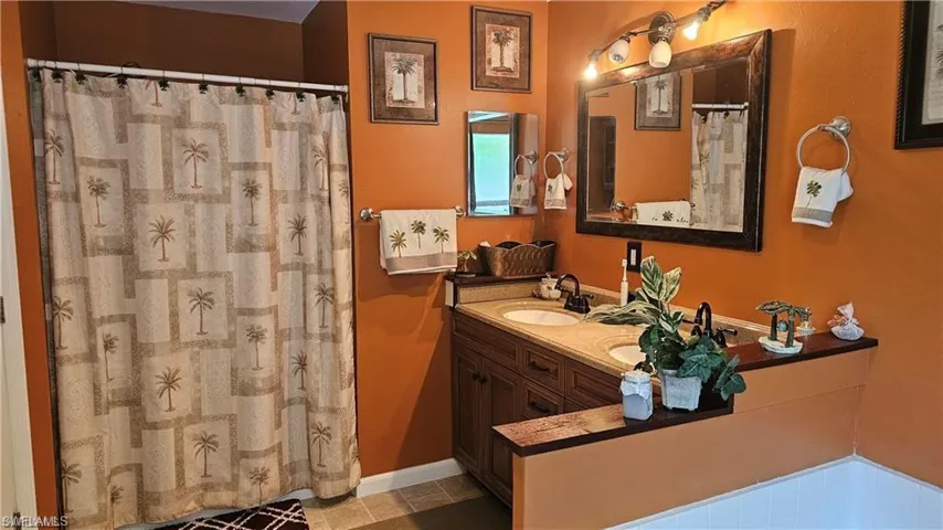 Bathroom with double vanity, tile patterned floors, and a shower with curtain