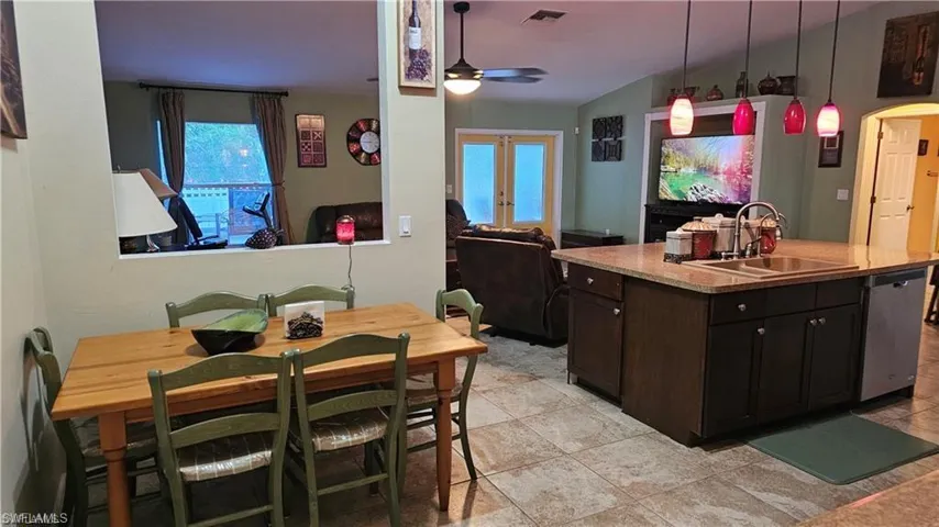 Kitchen with vaulted ceiling, a ceiling fan, healthy amount of natural light, stainless steel dishwasher, and light countertops