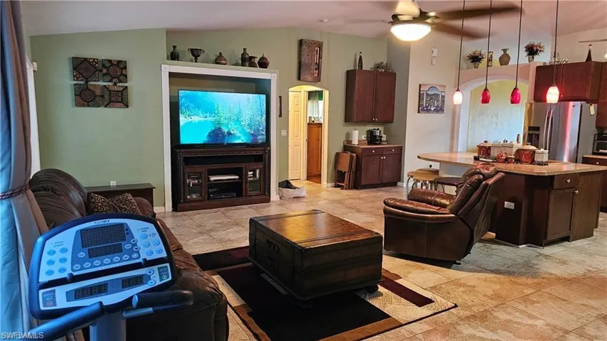 Living room with vaulted ceiling, ceiling fan, and arched walkways