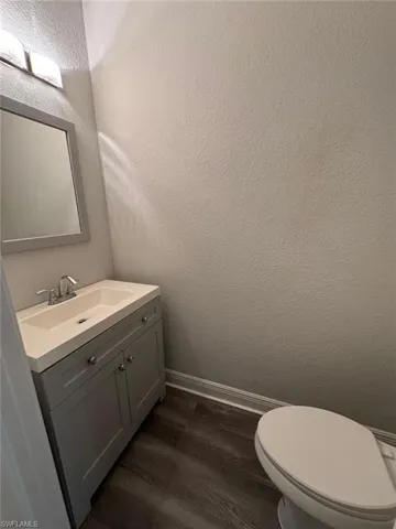 Bathroom featuring a textured wall, vanity, and dark wood-style flooring