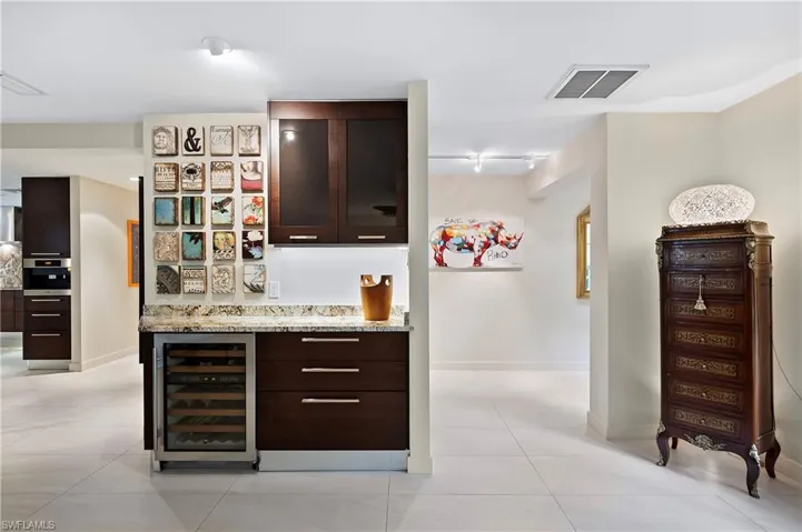 Bar with stainless steel oven, dark brown cabinets, light tile patterned floors, and wine cooler