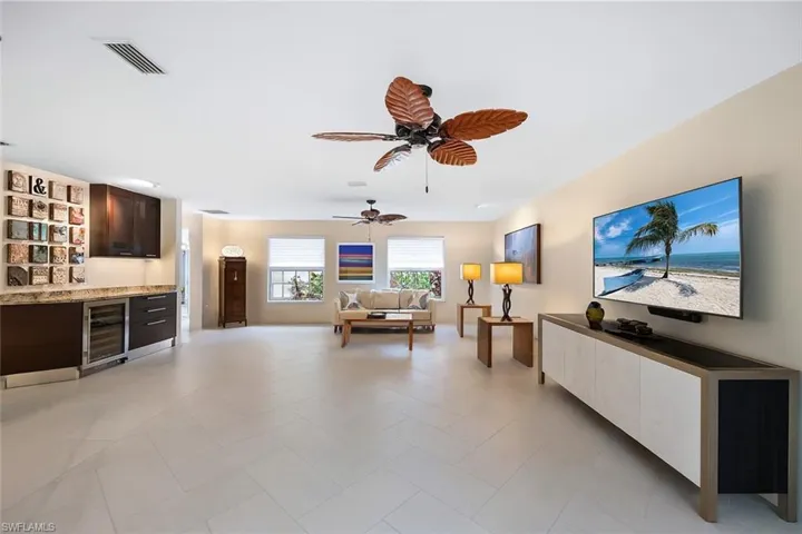 Living room featuring a bar, beverage cooler, and ceiling fan