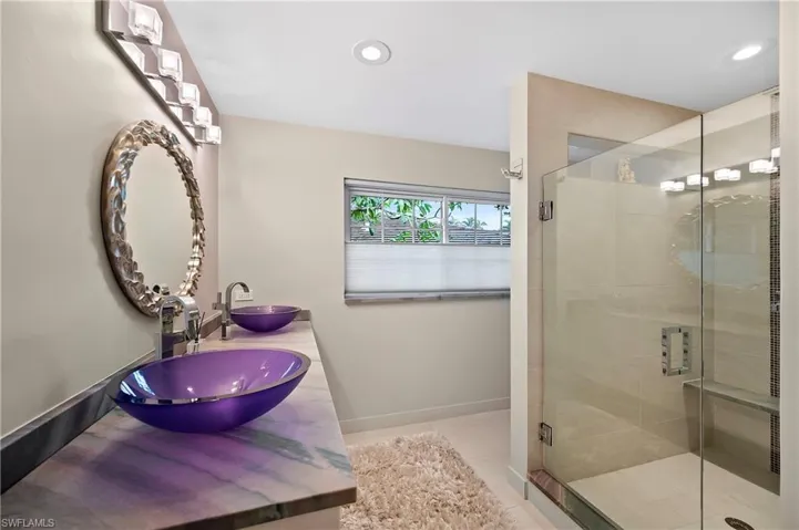 Bathroom featuring tile patterned floors, a shower with door, and dual bowl vanity