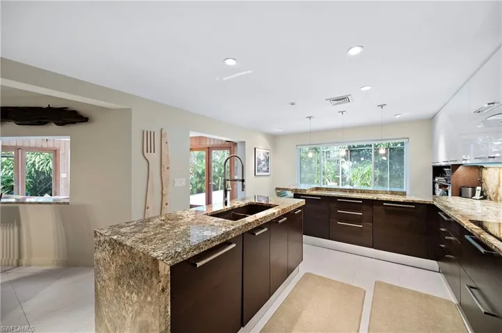 Kitchen with dark brown cabinetry, sink, a center island with sink, and light tile patterned floors