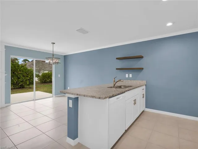 Dining Area With Sliders Leading To The Patio and Kitchen Island With Granite Countertop And Sink