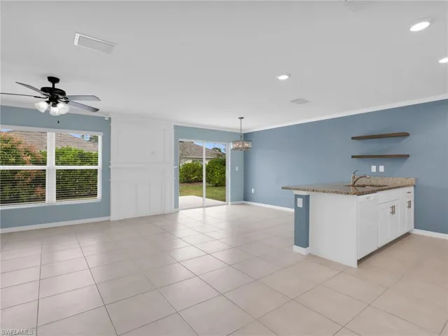 Great Room and Dining Area With Ceiling Fan, Chandelier, Tile Flooring, Faux Wood Blinds, Custom Woodwork Wall Feature, and Kitchen Island With Granite Countertop