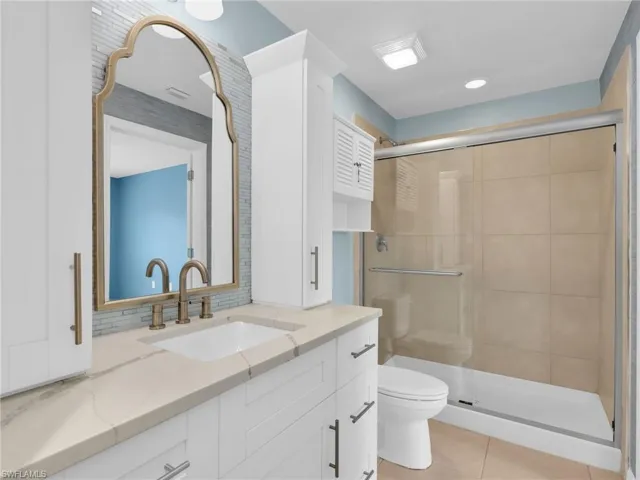 Primary En-Suite Bathroom With Renovated White Shaker Cabinetry With Drawers and Cabinet Towers, Added Backsplash, and Tiled Shower With Glass Enclosure