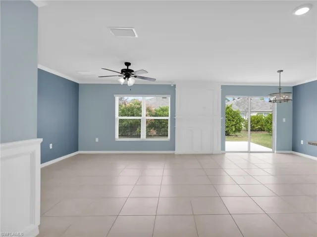 Great Room With Custom Woodwork Wall Feature, Crown Molding, Ceiling Fan, Chandelier, Tile Flooring, Faux Wood Blinds, and Sliders onto Patio