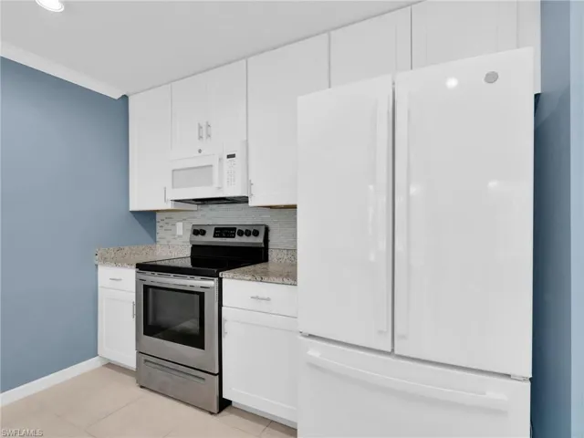 Kitchen With White Shaker Cabinets, Island, Granite Countertops, Added Backsplash, Pantry, New White GE Dishwasher, Microwave, And Refrigerator With Icemaker, And Stainless Steel Frigidaire Range With Self-Cleaning Oven.