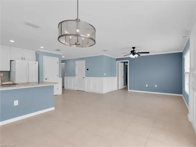 Great Room and Dining Area With Crown Molding, Chandelier, and Ceiling Fan, Kitchen With Island With Granite Countertop And Sink, White Shaker Cabinets, New White GE Dishwasher, Microwave, And Refrigerator, With Icemaker, And Stainless Steel Frigidaire Range With Self-Cleaning Oven