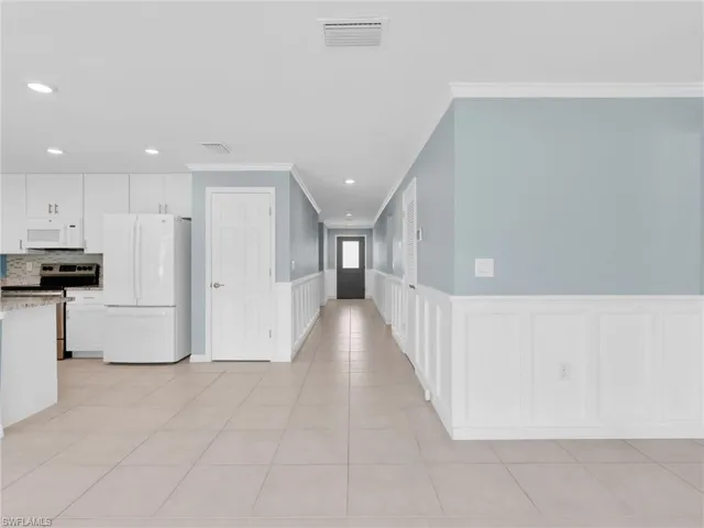 Foyer And Entry Hallway With Crown Molding and Wainscotting, Kitchen With Tile Flooring and New White GE Dishwasher, Microwave, And Refrigerator With Icemaker, And Stainless Steel Frigidaire Range With Self-Cleaning Oven