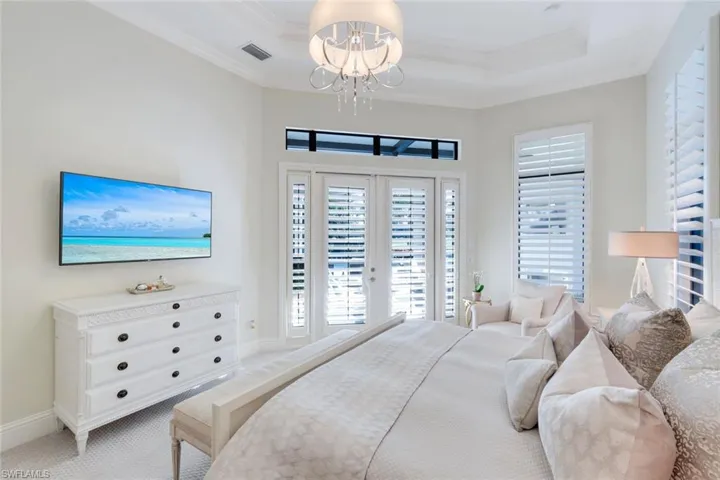 Bedroom with access to exterior, plantation shutter, french doors, crown molding, carpet, and a tray ceiling