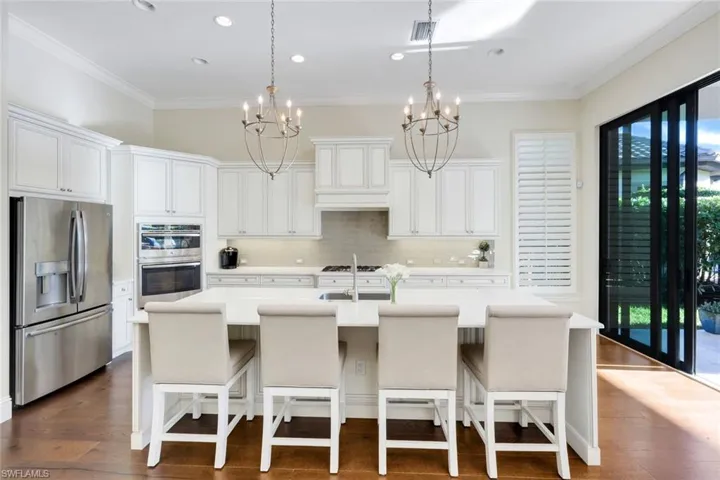 Kitchen featuring stainless steel appliances, a breakfast bar area, crown molding, white cabinets, and an island with sink