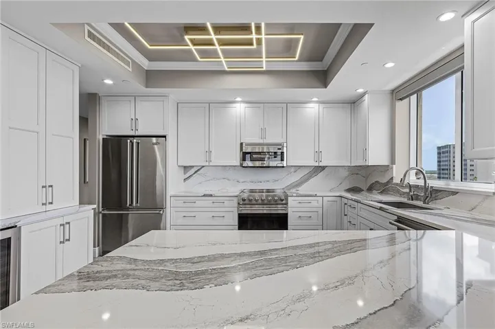 Kitchen featuring sink, high quality appliances, a raised ceiling, and ornamental molding