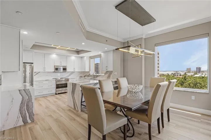 Dining space with light hardwood / wood-style floors, crown molding, plenty of natural light, and a tray ceiling