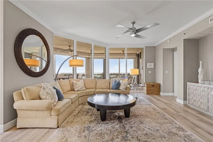 Living room featuring a wall of windows, light hardwood / wood-style floors, ornamental molding, and ceiling fan