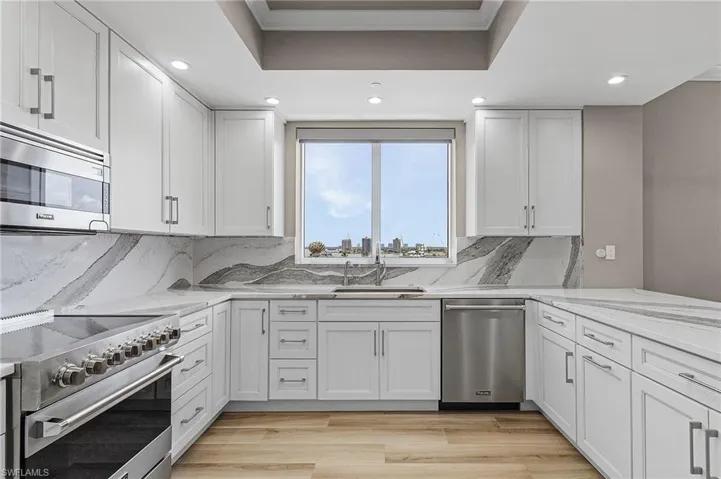 Kitchen featuring white cabinetry, light stone countertops, light hardwood / wood-style flooring, and stainless steel appliances