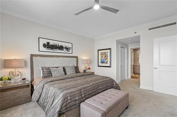 Bedroom featuring ensuite bath, ceiling fan, ornamental molding, and light colored carpet