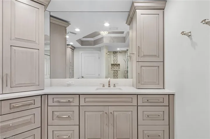 Bathroom featuring vanity, crown molding, and a raised ceiling