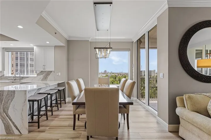 Dining space featuring sink, light wood-type flooring, ornamental molding, and a notable chandelier
