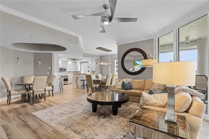 Living room featuring ornamental molding, light wood-type flooring, and ceiling fan