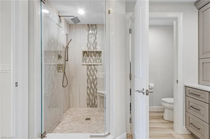 Bathroom featuring toilet, hardwood / wood-style floors, and a tile shower