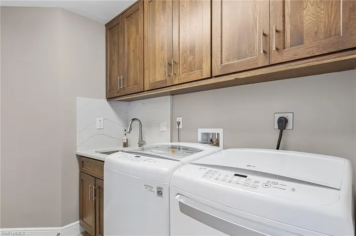 Washroom featuring sink, cabinets, and washing machine and clothes dryer