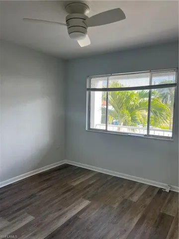 Unfurnished room with dark wood finished floors and a ceiling fan