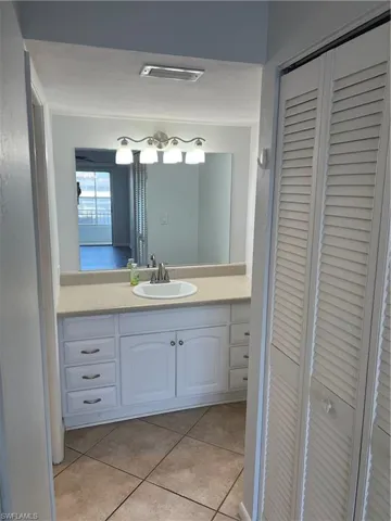 Bathroom featuring a closet, vanity, and light tile patterned floors