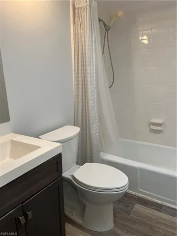 Bathroom with vanity, dark wood-type flooring, and shower / bath combo with shower curtain