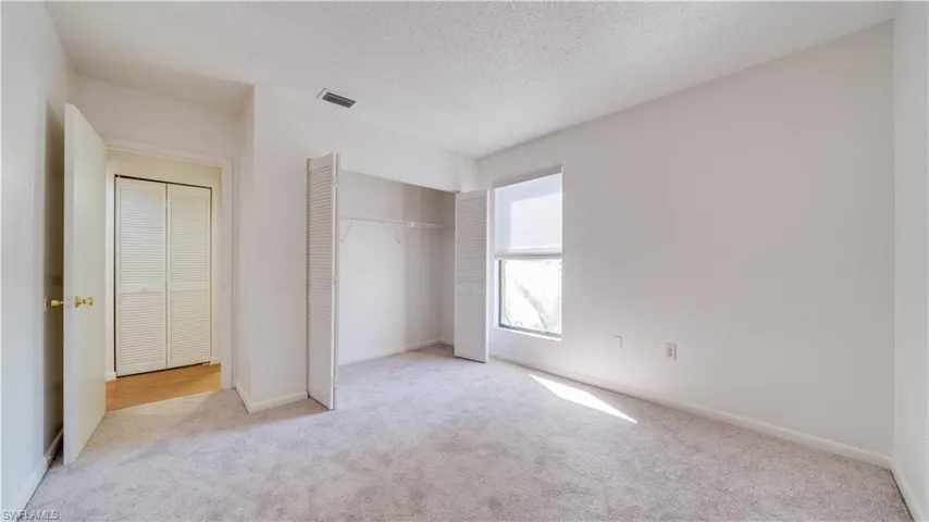 Unfurnished bedroom featuring a textured ceiling, light colored carpet, and a closet