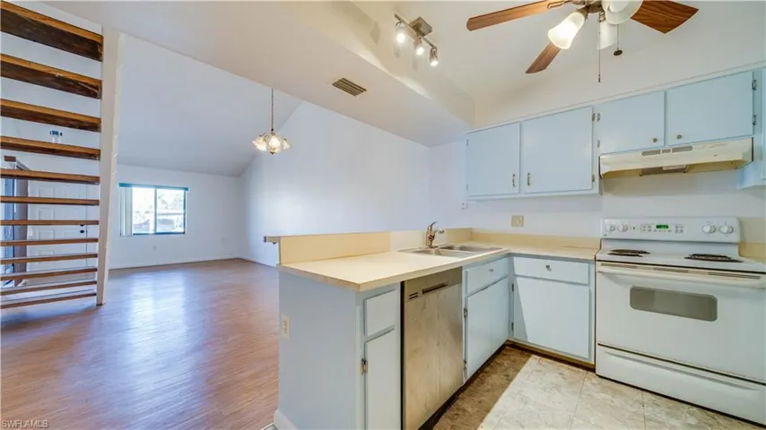 Kitchen with white range with electric stovetop, decorative light fixtures, a peninsula, light countertops, and open floor plan