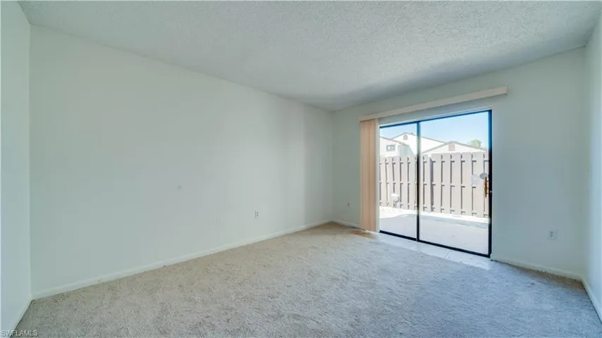 Empty room with a textured ceiling and carpet flooring