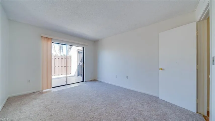 Carpeted empty room with a textured ceiling and baseboards
