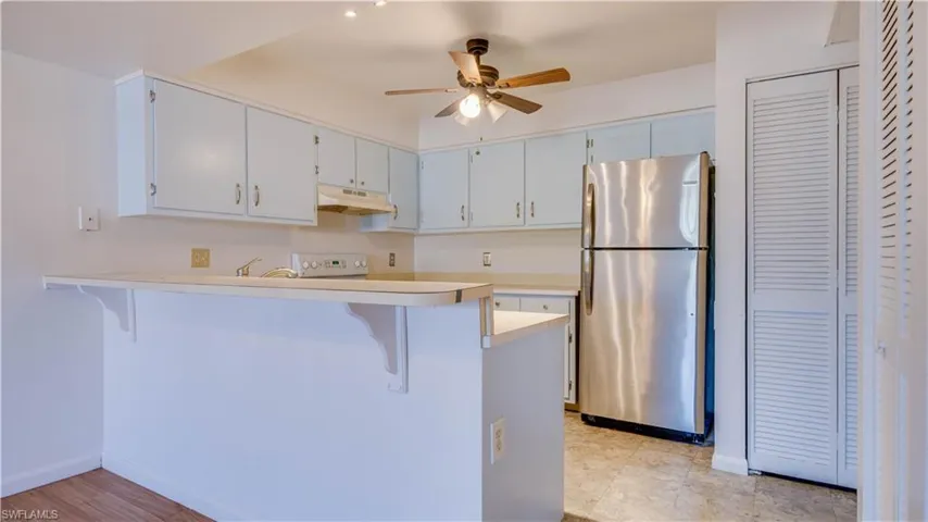 Kitchen with a kitchen bar, freestanding refrigerator, a peninsula, and light countertops