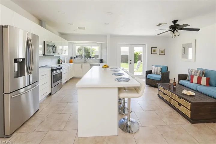 Kitchen with stainless steel appliances, a breakfast bar area, open floor plan, decorative backsplash, and white cabinets
