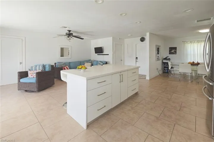 Kitchen featuring light tile patterned floors, light countertops, white cabinets, freestanding refrigerator, and a center island