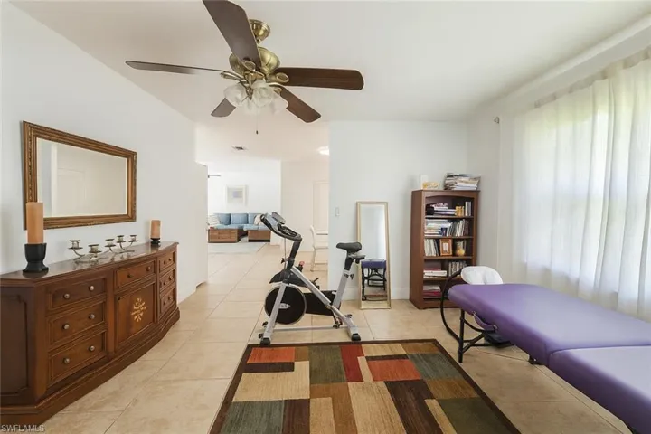 Exercise area with light tile patterned flooring and ceiling fan