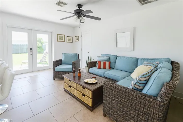 Living room featuring french doors, light tile patterned floors, and ceiling fan