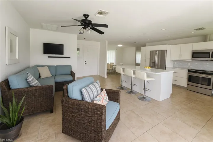 Living room with light tile patterned floors, ceiling fan, and recessed lighting
