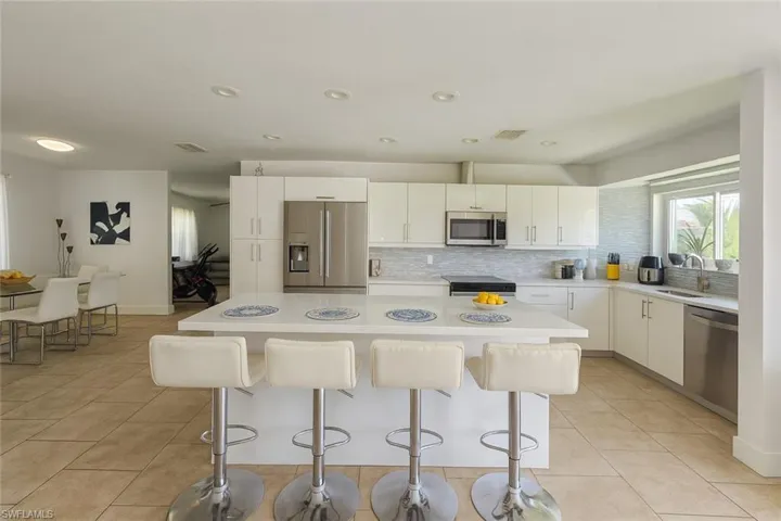 Kitchen featuring appliances with stainless steel finishes, light countertops, light tile patterned flooring, a breakfast bar area, and recessed lighting