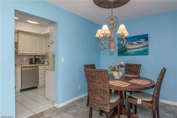 Dining area featuring a decorative chandelier with shades, an arched entryway, and tile flooring