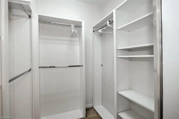 Built-in white shelving system with multiple chrome hanging rods and adjustable shelving
