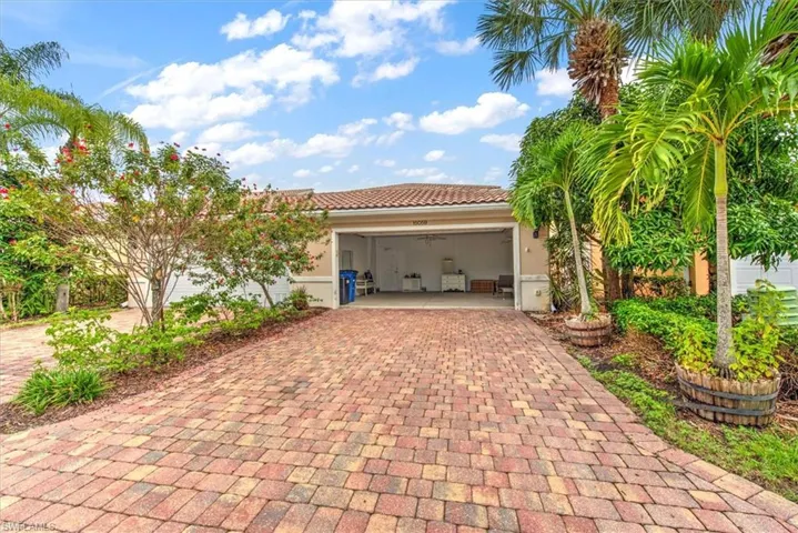 Paver driveway leading to an attached garage with a tile roof